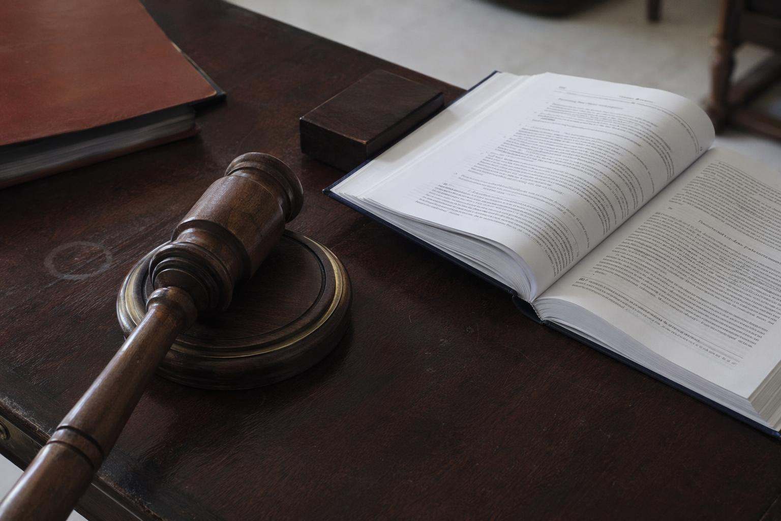 Mazo de juez sobre mesa de juzgado con código penal abierto, abogados penalistas Alicante