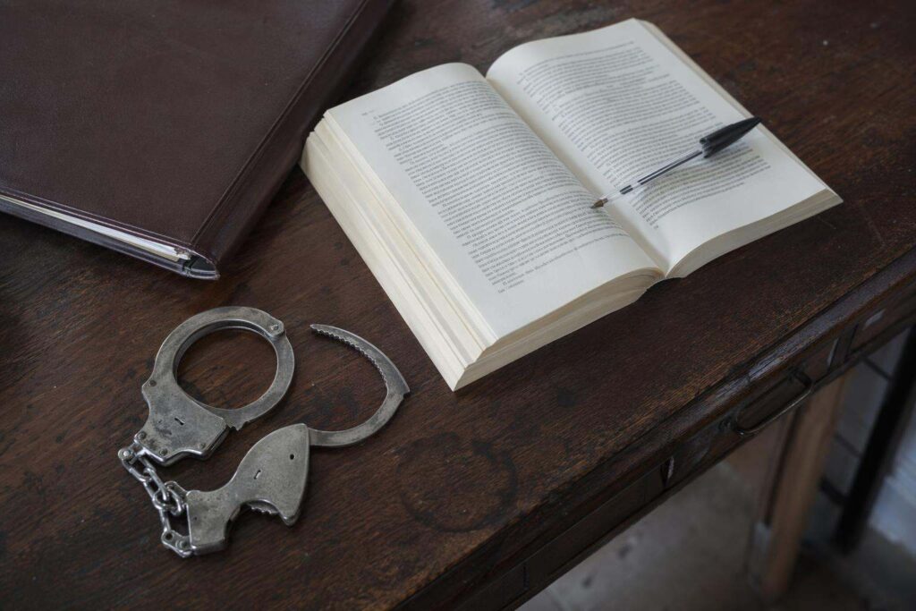 Esposas y código penal abierto sobre escritorio antiguo, abogados penalistas Ávila