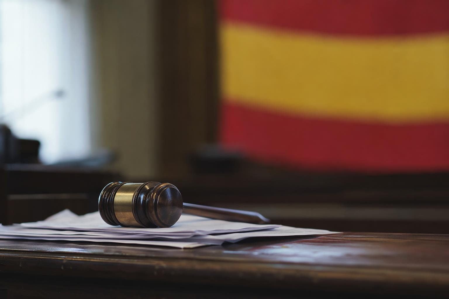 Mazo de juez en mesa de juzgado con bandera de España difuminada — despacho de abogados penalistas Huesca