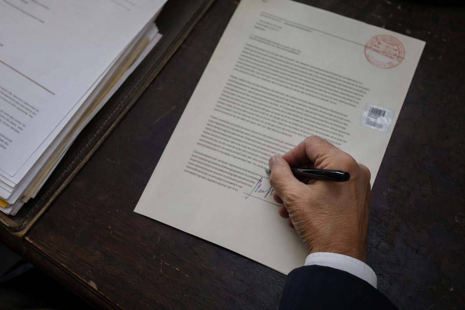 Detalle de pluma firmando escrito procesal con sello de procurador, abogados penalistas en Pontevedra