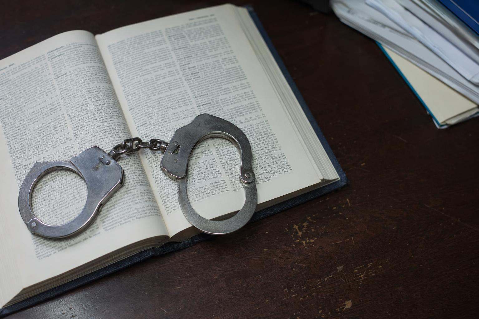 Esposas de acero sobre Código Penal abierto en despacho de abogados penalistas en Salamanca