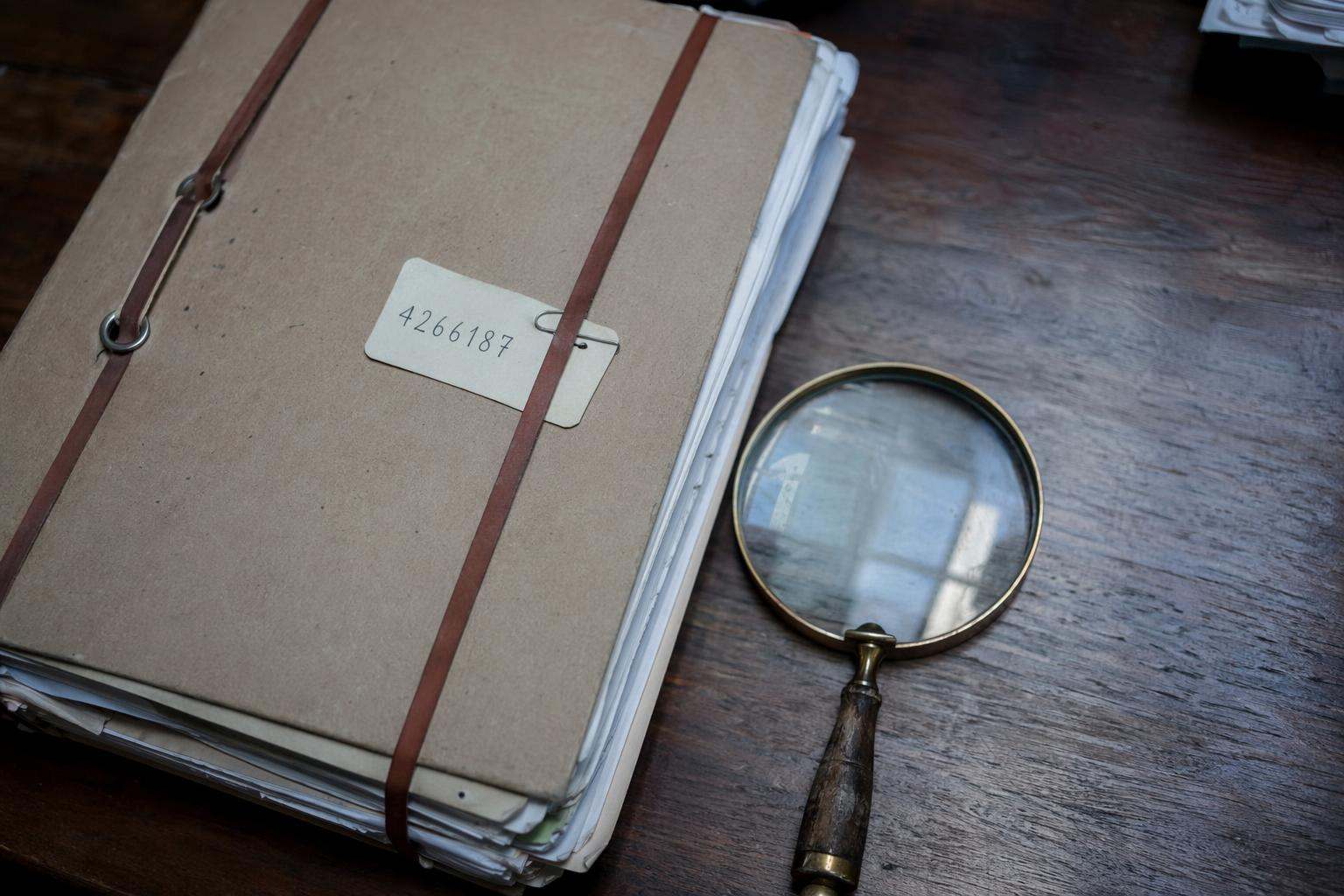 Expediente judicial voluminoso etiquetado con lupa sobre escritorio de abogados penalistas en Tarragona