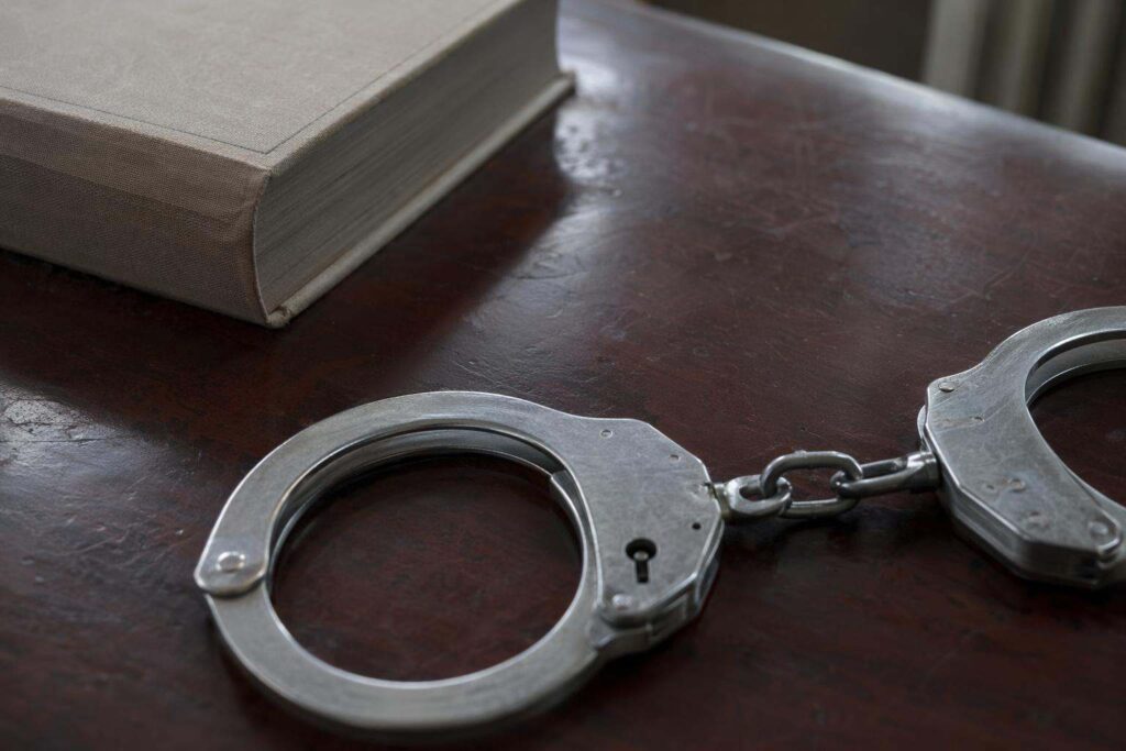 Esposas de acero sobre escritorio de mahogany oscuro en despacho de abogados penalistas en Tenerife