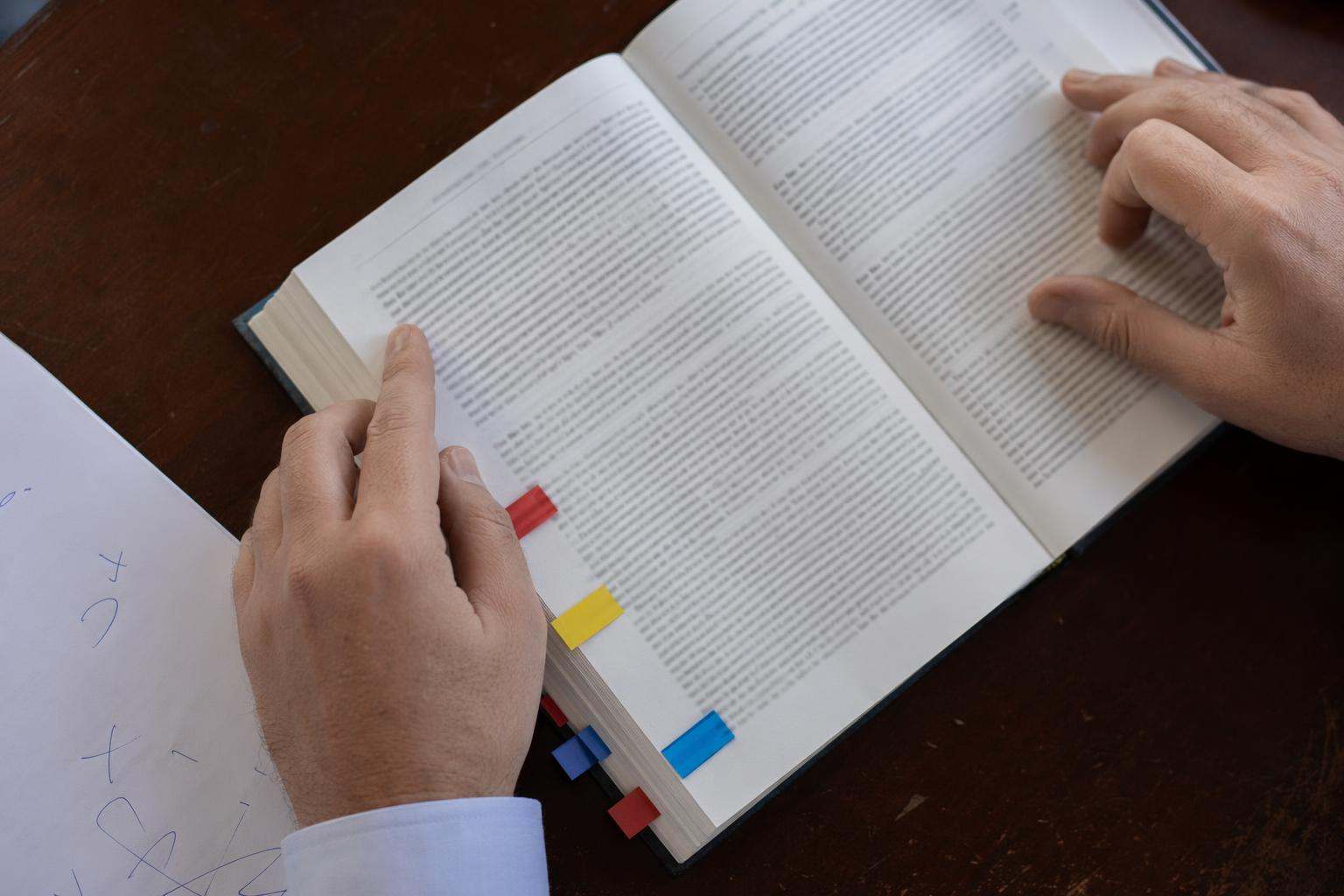 Manos de letrado sosteniendo código constitucional con marcadores de colores preparando recurso de amparo ante el Tribunal Constitucional