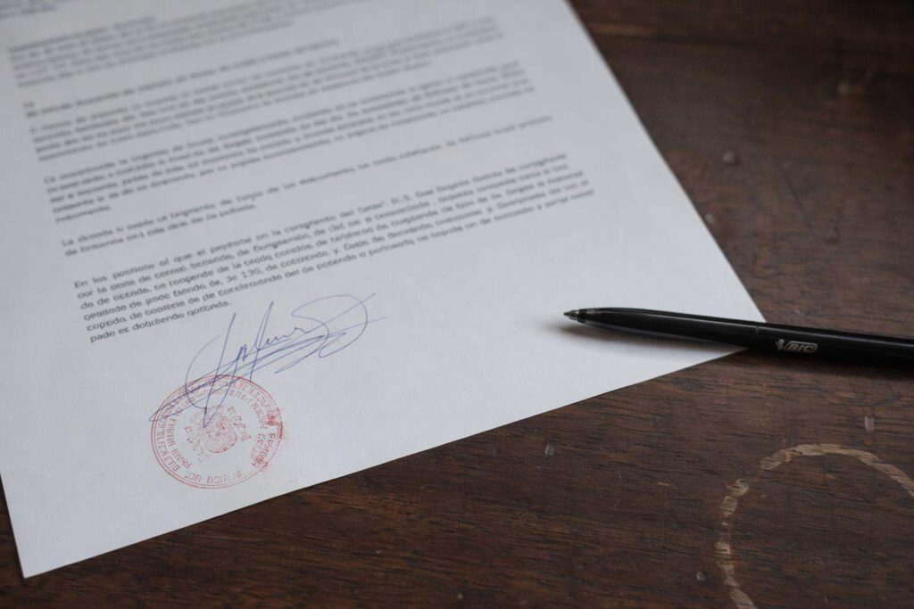 Sello procesal rojo sobre escrito firmado con bolígrafo en mesa de despacho de abogado penalista en Vitoria
